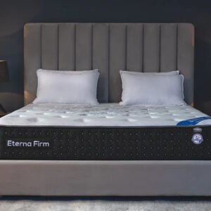 Celeste Eterna Firm mattress in a modern bedroom with gray headboard, white bedding, and black side panel featuring tufted design and certification badge.